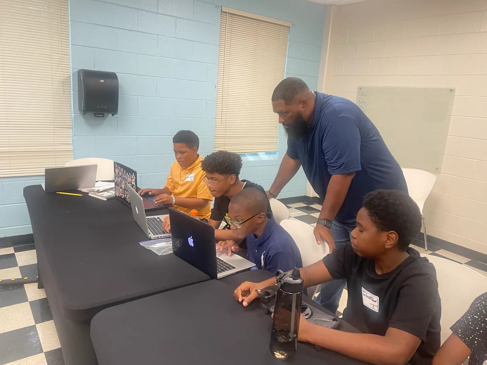 Mentor helping a student at a laptop