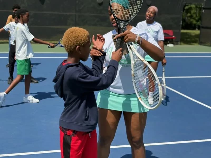 A coach working with young players on the tennis court