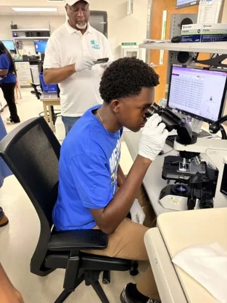 Student in gloves examining a slide